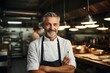 Middle aged french caucasian chef working in a restaurant kitchen smiling portrait