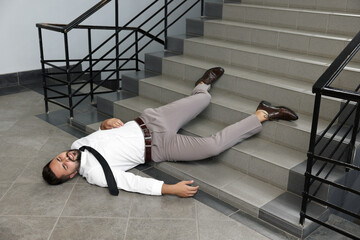 Wall Mural - Unconscious man lying after falling down stairs indoors