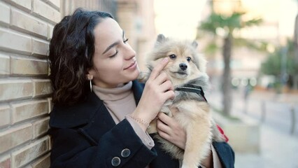 Wall Mural - Young hispanic woman with dog smiling confident standing at street