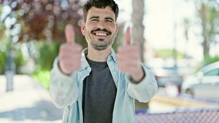 Poster - Young hispanic man smiling confident doing ok sign with thumbs up at park