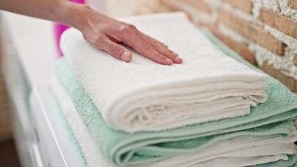 Sticker - Young hispanic man touching folded towels at laundry room