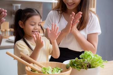 Wall Mural - Happiness asian family with father, mother and daughter preparing cooking salad vegetable food together in kitchen at home, happy dad, mom and kid cooking breakfast with salad, lifestyles concept.