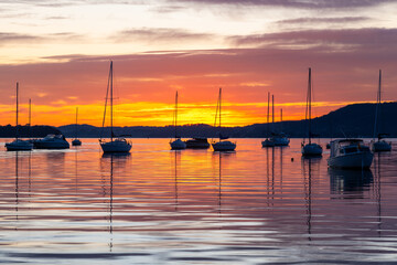 Wall Mural - Sunrise over the water with boats, reflections and high cloud