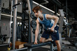 Concentrated teenager boy training arm and shoulders muscles with dumbbells