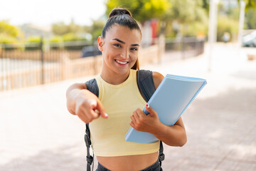 Wall Mural - Young pretty student woman at outdoors points finger at you with a confident expression