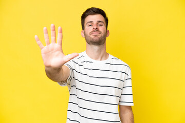 Wall Mural - Young caucasian man isolated on yellow background counting five with fingers