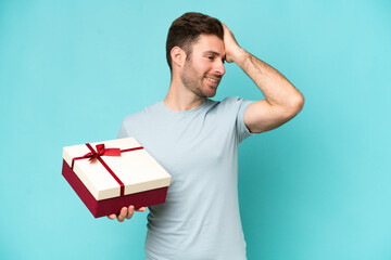 Wall Mural - Young caucasian man holding a gift isolated on blue background has realized something and intending the solution