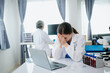 © laddawan - Confident young Caucasian female doctor in white medical uniform sit at desk working on computer. Smiling use laptop write in medical journal