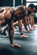 © OMD - closeup shot of a group of people doing push ups together during their workout at the gym