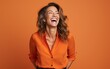 © hakule - happy 40 years old businesswoman, who is smiling and laughing, wearing bright clothes. orange background, studio photos. created by generative AI technology.