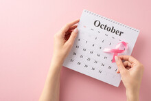 My Breast Cancer Awareness Setup. First Person Top View Of Girl's Hands Holding October Calendar With Pink Ribbon, Gearing Up For Doctor's Visit On Pastel Pink Background With Blank Area For Text