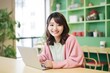 © mockupzord - A smiling woman sits at a desk with a laptop, her bright clothing a cheerful contrast to the plain walls of the indoor room