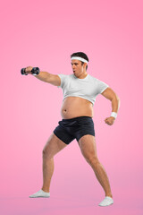 Wall Mural - A funny fat man with dubbell isolated on pink background. Obesity and eating disorder. Concept for dietetics and fitness advertising in social networks.