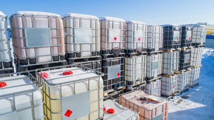 Poster - Plastic tanks on pallets. Containers for storage and transportation of liquids. Warehouse of plastic barrels. Cisterns are stored in snow. Tanks in metal crate. Tanks for chemical products
