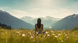 An image of a person from behind meditating in a field of wildflowers with mountains in the distance.