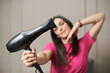 © pridannikov - A woman holds a hair dryer on the background of her face, the concept of hair care