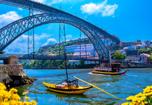 Landscape View Of The Famous I Luiz Ponte Across The River Douro And Transportation Bu Traditional Yellow Boats In Porti City, Portugal