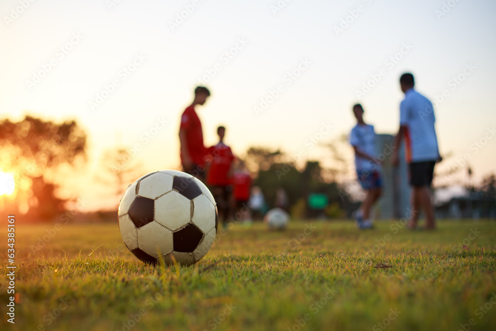 Action sport outdoors of kids having fun playing soccer football for exercise in community rural area under the twilight sunset sky. Picture with copy space.