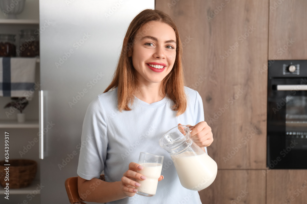 Young woman pouring milk into glass in kitchen