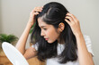 © KMPZZZ - Damaged hair symptom, problem hair fall asian young woman, girl worry about balding, looking at scalp in mirror, hand in break into front hair loss, thin problem. Health care treatment for beauty.