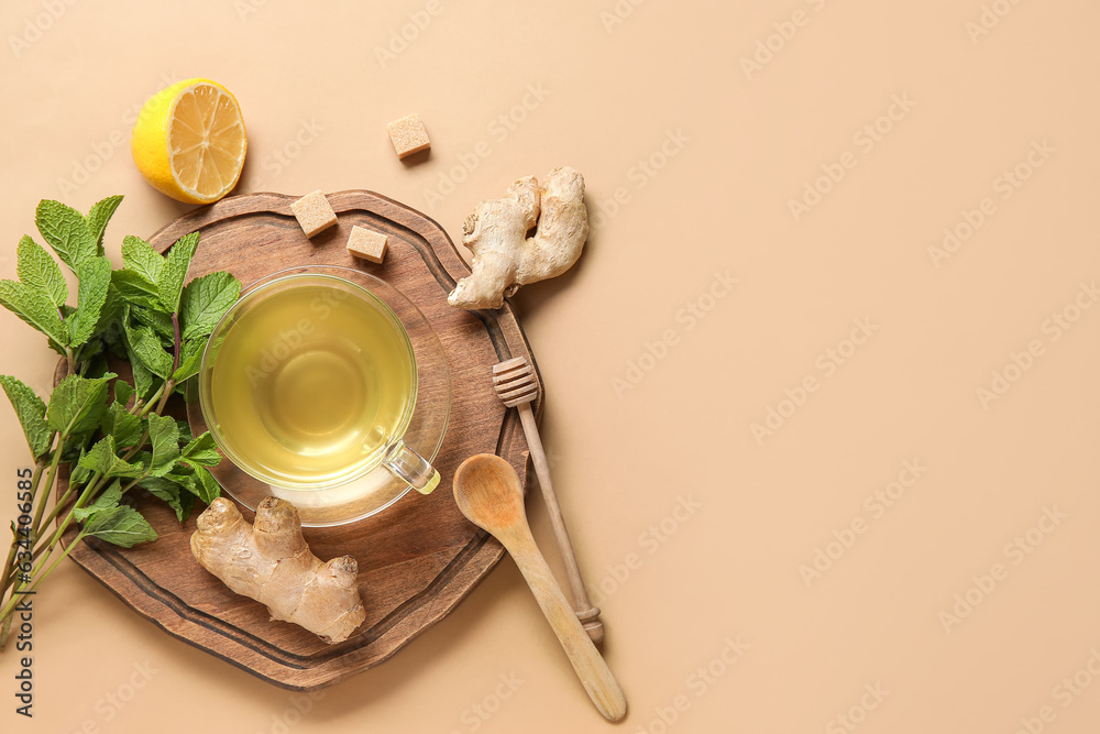 Glass cup of ginger tea with lemon and mint on brown background