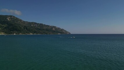 Wall Mural - A small motorboat cruises through the stunning turquoise waters of the Greek islands' serene sea