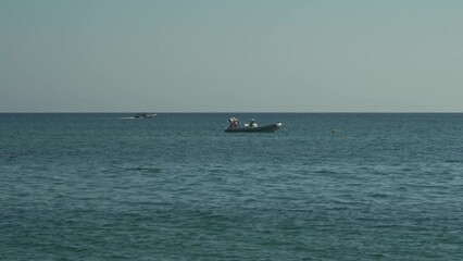 Wall Mural - Video of boats gently swaying in the sunny sea, moored not far from the beach, on a hot day