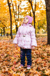 © Mariia - Positive little girl playing in the autumn park. Happy emotional child catches maple leaves. active holiday in autumn. leaf fall