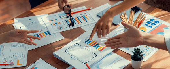 Analyst team utilizing BI Fintech to analyze and pointing at financial dashboard paper office. Businesspeople examining report paper on table for business insight. Panorama shot. Scrutinize