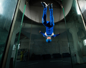 Wall Mural - A man in overalls and a protective helmet enjoys flying in a wind tunnel. Free fall simulator