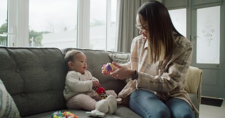 Canvas Print - .Mother, baby and playing with toys, sofa and bonding with care, learning and development with smile in house. Mom, infant kid and playful with love, talking and teaching motor skills in family home.