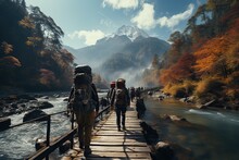 Adventurous Travelers, With Backpackers Exploring A Scenic Mountain Trail, Crossing Wooden Bridges Over A Glistening River