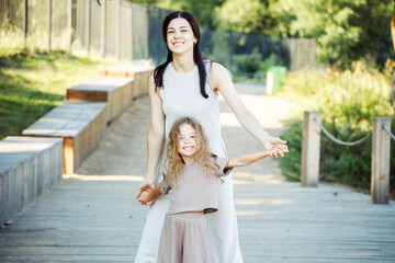 A little daughter holds her mother's hand. Mother and daughter walk in the Park