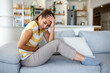 © Graphicroyalty - Woman lying on sofa looking sick in the living room. Beautiful young woman lying on bed and holding hands on her stomach. Woman having painful stomachache on bed, Menstrual period