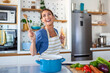 © Graphicroyalty - Funny beautiful woman singing into spatula, cooking in modern kitchen, holding spatula as microphone, dancing, listening to music, playful girl having fun with kitchenware, preparing food.