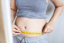 Obese Woman Checking Her Fat  Belly With A Measuring Tape, Weight Gain Concept 