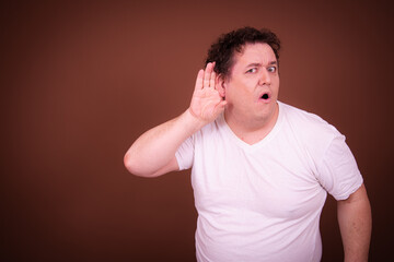 Wall Mural - Funny fat man posing on a brown background.