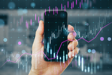 Wall Mural - Close up of male hand holding mobile phone with creative candlestick forex chart hologram on blurry office interior background. Trade, stock and mobile banking concept. Double exposure.