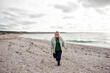 © Вероника Зеленина - Beautiful woman walking in the sand beach in cold weather. Overweight model have fun . The happy girl wearing knit polluver