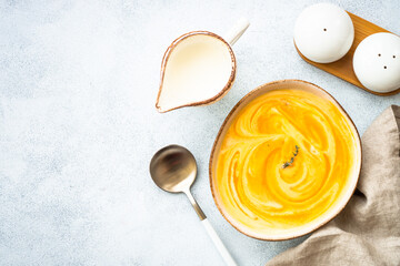 Wall Mural - Pumpkin soup with cream in the craft bowl at stone table. Healthy eating. Top view with copy space.