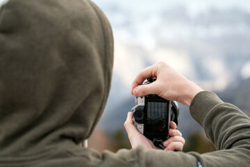 Amateur Photographer Capturing Mountain Moments with Modern Camera. Screen visible. Camera LCD screen as a viewfinder