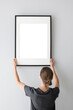 © kite_rin - Woman hold blank picture frame mockup on white wall, Artwork mock-up in minimal interior design, Minimal photographer artist concept