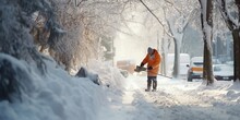 A Janitor With A Shovel Walks Along A Snow-covered Sidewalk.
