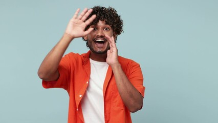 Wall Mural - Young Indian man wear red shirt casual clothes look around for friend find waving meet greet with hand as notices someone say hello hi isolated on pastel plain blue cyan background. Lifestyle concept