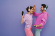 © Drobot Dean - Young couple dancing while listening music with headphones and mobile phones isolated over purple background