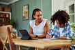 © bnenin - African American woman overseeing a teenager who is doing his homework.