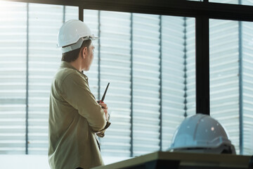 Wall Mural - Young Asian engineer talking radio walkie talkie to operate and control the worker employee to build construction.