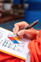 Wall Mural - a safety engineer is using pen to rating the health risk assessment level of chemical hazardous mate