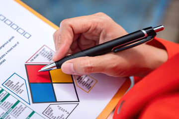 Wall Mural - a safety engineer is using pen to rating the health risk assessment level of chemical hazardous mate