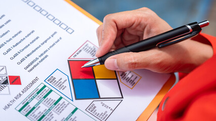 Wall Mural - a safety engineer is using pen to rating the health risk assessment level of chemical hazardous mate